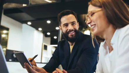 two people smiling and discussing over a tablet